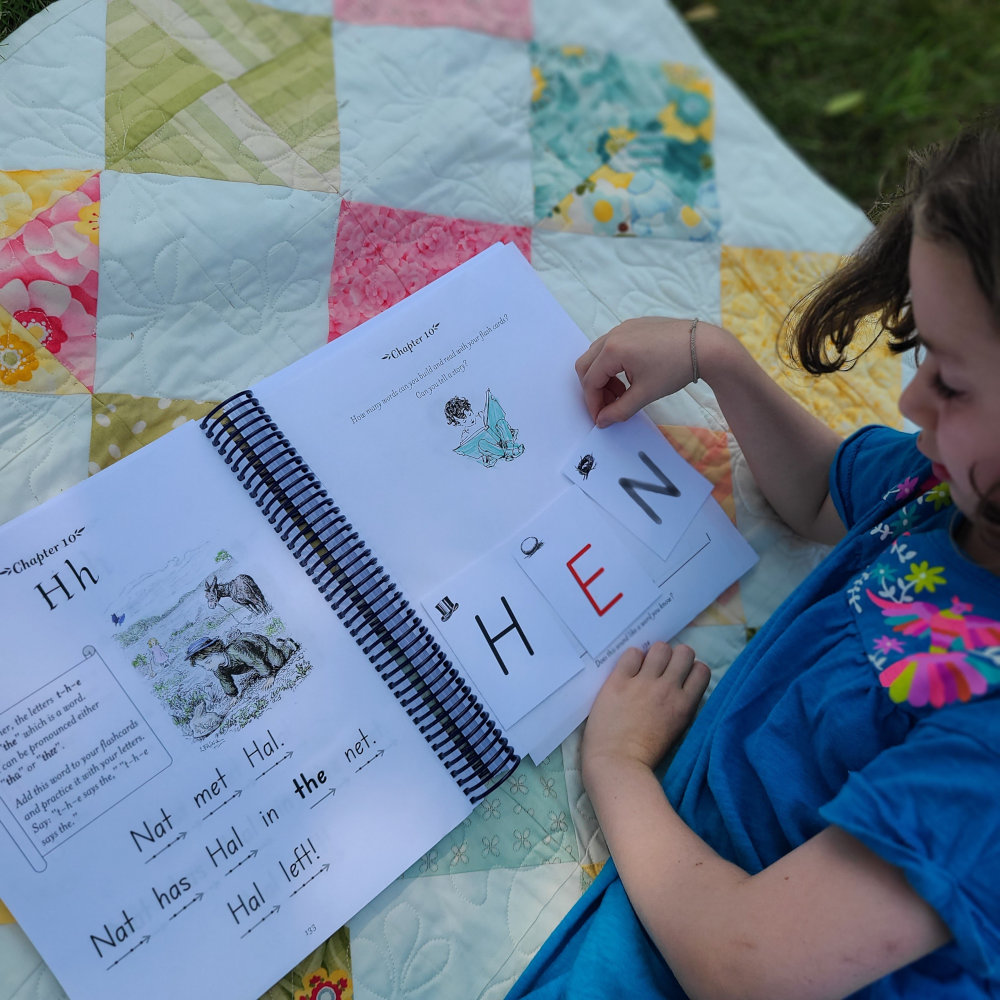 A young child looks at a phonics curriculum page
